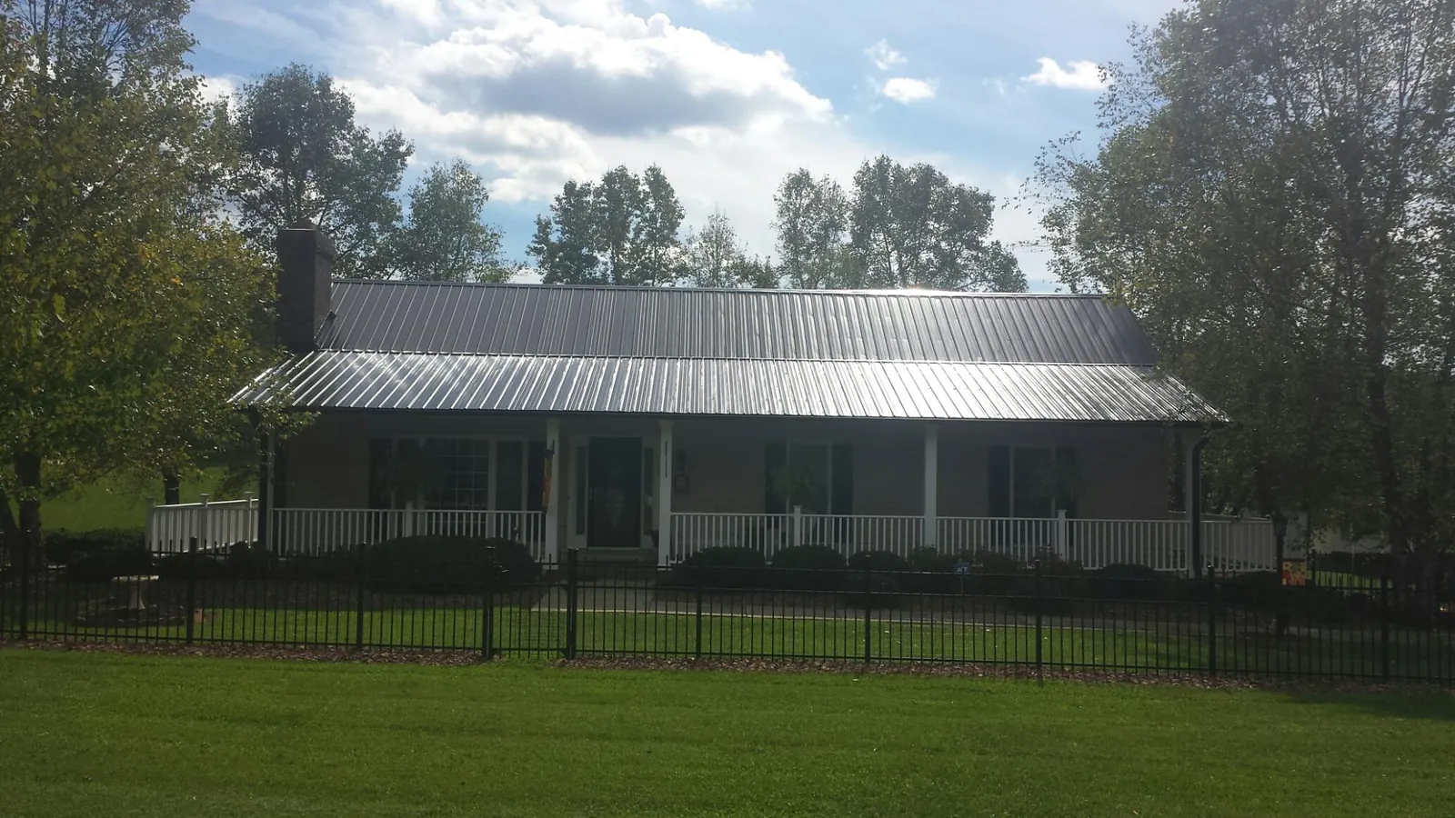 Gray metal roof on a brick ranch with a full width front porch — Gutter Guard Installation work by our crew in Penrose